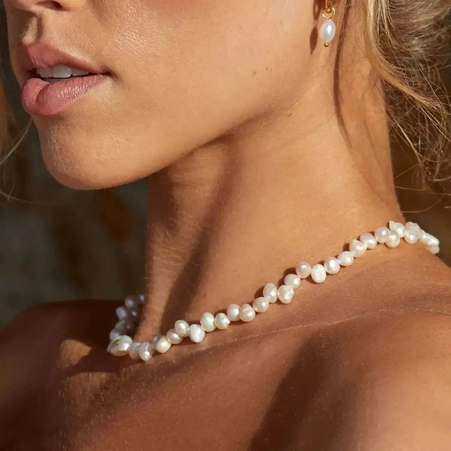 Woman wearing a natural freshwater pearl strand necklace and matching pearl earring
