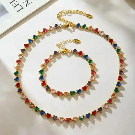 Gold necklace and bracelet set with multicolor heart-shaped gemstones on white background