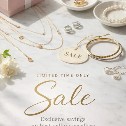 Gold necklaces, rings, and bangles on marble with sale tag, jewellery gift box and flowers.