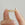 Gold ring with pearls held between two fingers against a neutral background