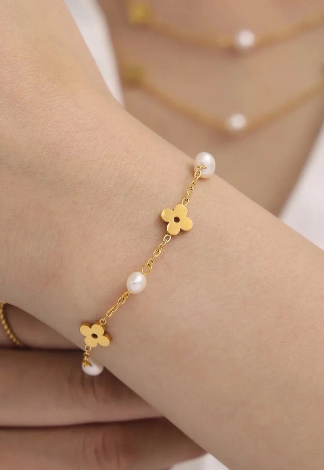 Gold bracelet with floral designs and pearls on a wrist