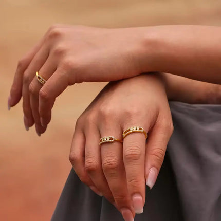 Close-up of hands wearing gold rings on a warm-toned background