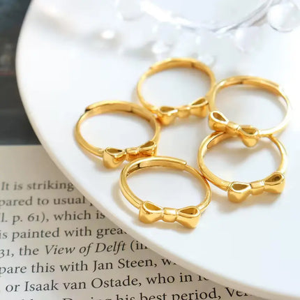 Gold bow-shaped rings on a white surface with text in the background