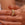 Gold ring with diamonds on a person's finger against a neutral background