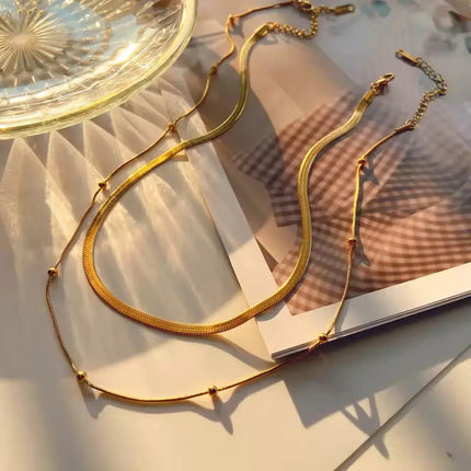 Gold necklace on a textured surface with a glass dish in the background