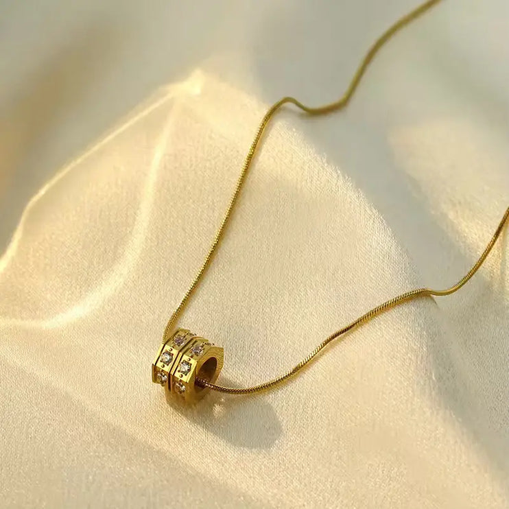 Gold necklace with a beaded pendant on a beige fabric background