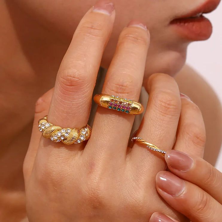 Close-up of a hand wearing two gold rings with gemstones.