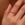 Gold ring with small diamonds on a person's finger against a neutral background