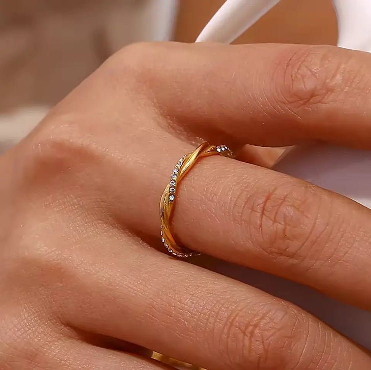 Close-up of a hand wearing a gold ring with small stones.