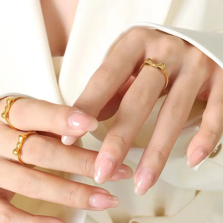 Close-up of hands wearing gold rings on a light background