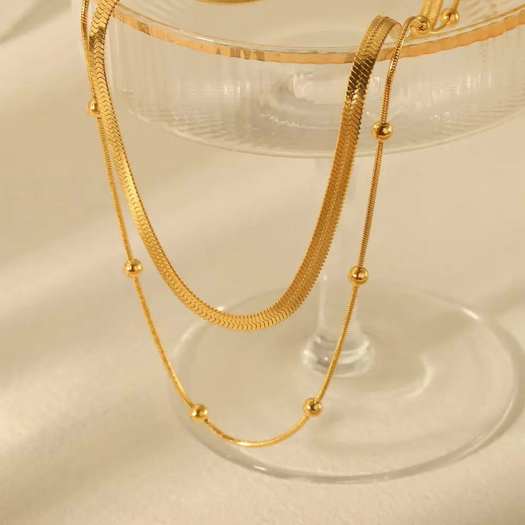 Gold necklace on a soft beige glass background