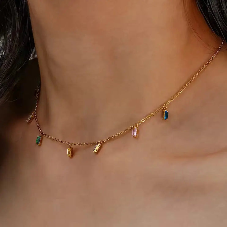 Gold necklace with colorful gemstones on a person's neck