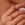 Close-up of a hand wearing two gold rings with gemstones on a neutral background