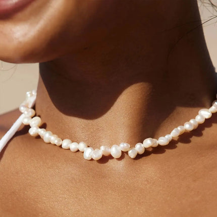 Pearl necklace on a person's neck with a neutral background