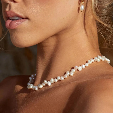 Close-up of a woman wearing a pearl necklace and earrings.