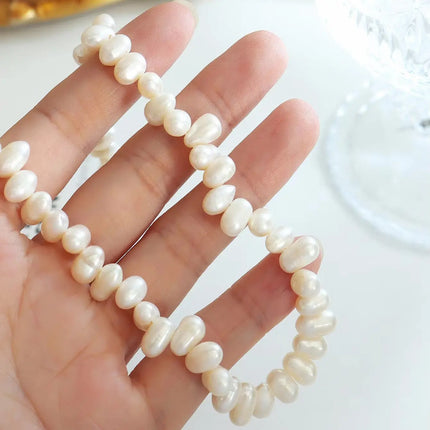 Pearl necklace draped over a hand on a light background