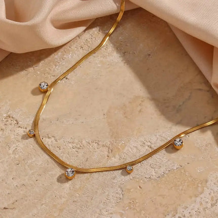 Gold necklace with small crystals on a beige fabric background