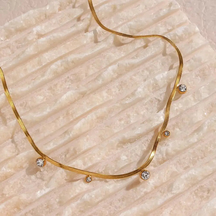 Gold necklace with small diamonds on a textured beige surface