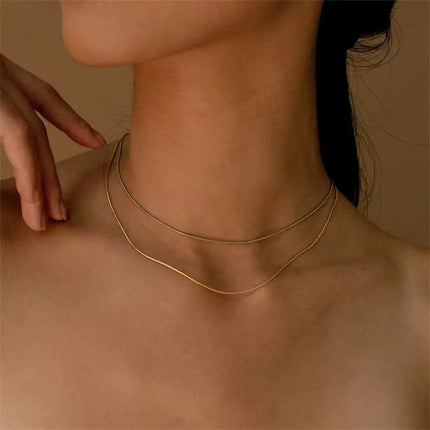 Gold necklace on a person's neck with a neutral background