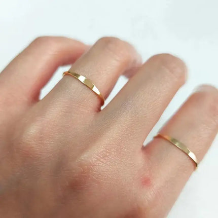 Hand wearing two gold rings on a white background
