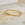 Gold stainless steel bangle with row of small crystals, minimalist jewelry on stone surface