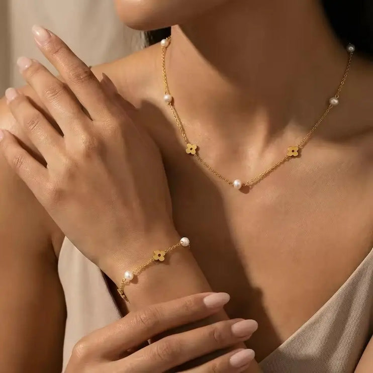 Gold bracelet with floral designs and pearls on a wrist