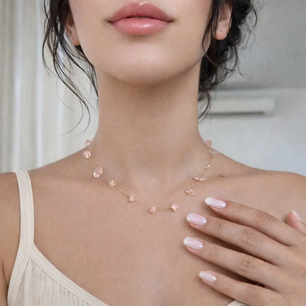 Woman wearing a delicate pink necklace with a neutral background