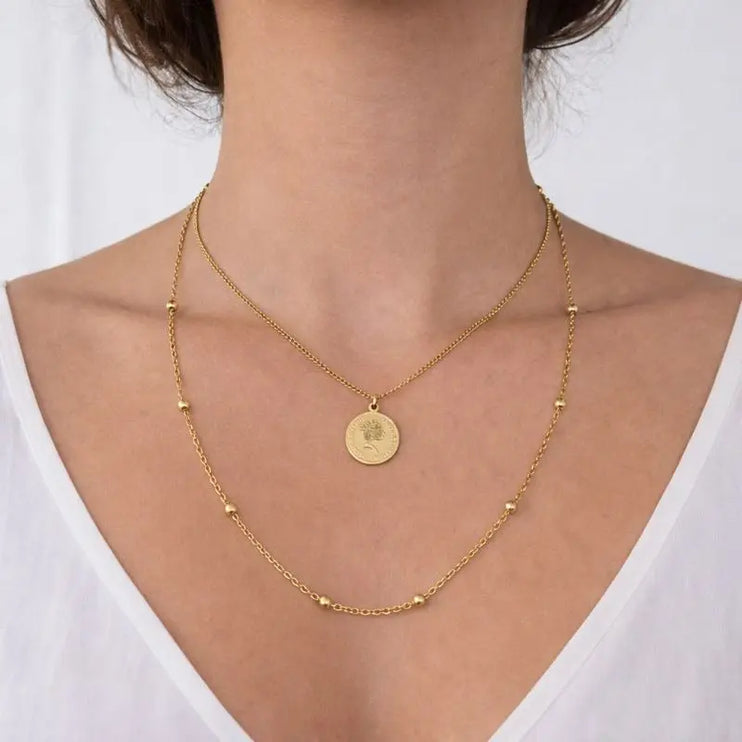 Gold necklace with a pendant on a person wearing a white top