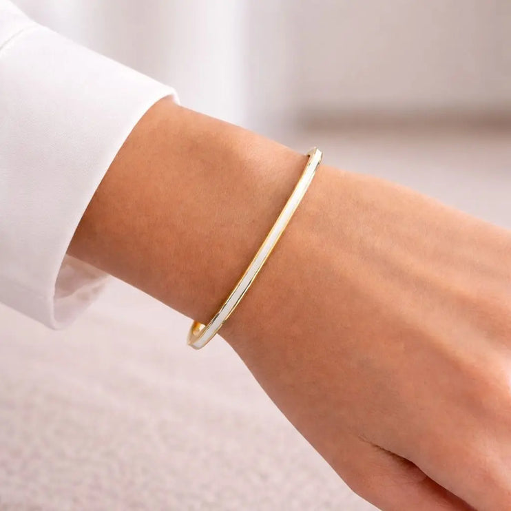 Gold bracelet on a person's wrist with a light background