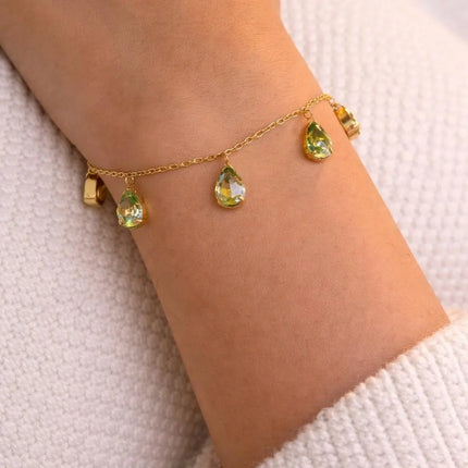 Gold bracelet with green gemstones on a wrist against a white background