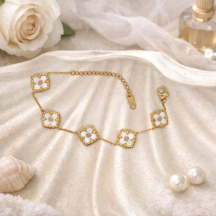 Gold bracelet with floral designs on a soft beige fabric background