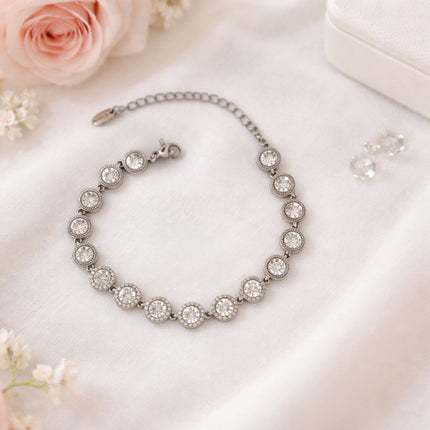 Silver bracelet with clear stones on a light pink surface with flowers