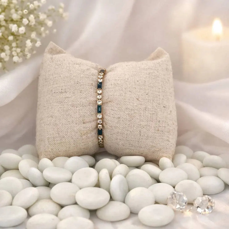 Bracelet on a beige fabric pillow with white stones and a blurred candle in the background