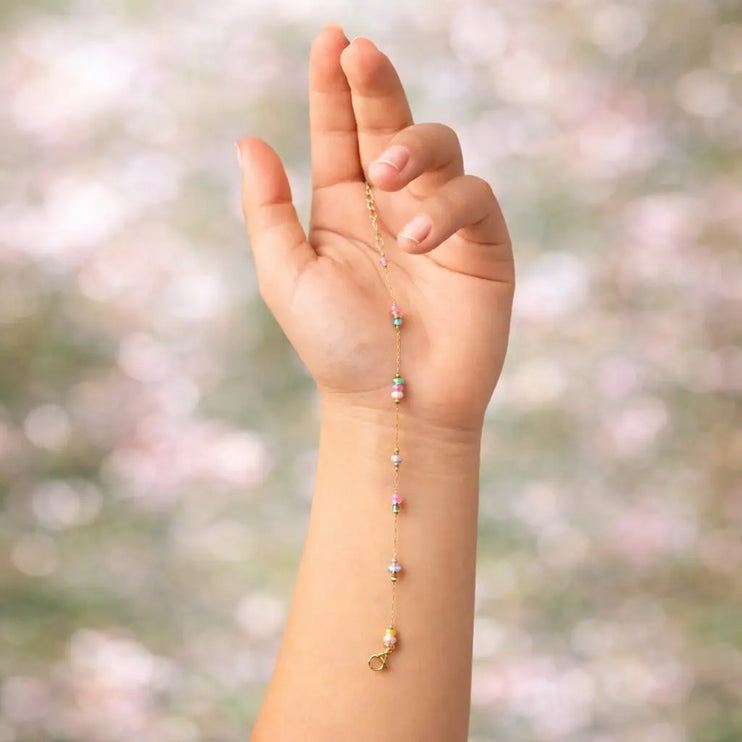 Hand wearing a delicate bracelet with a blurred natural background