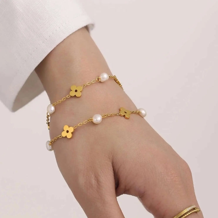 Gold bracelet with floral designs and pearls on a wrist