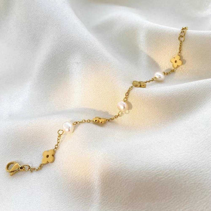Gold bracelet with floral designs and pearls on a wrist