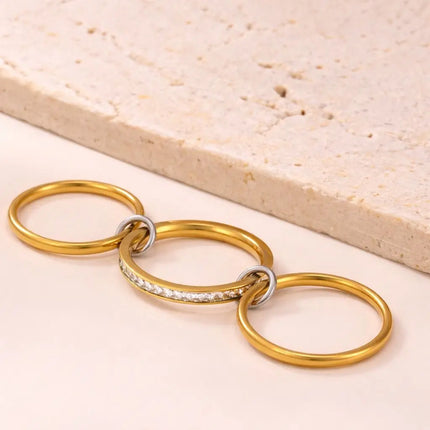 Gold keychain with interlocking rings on a beige surface
