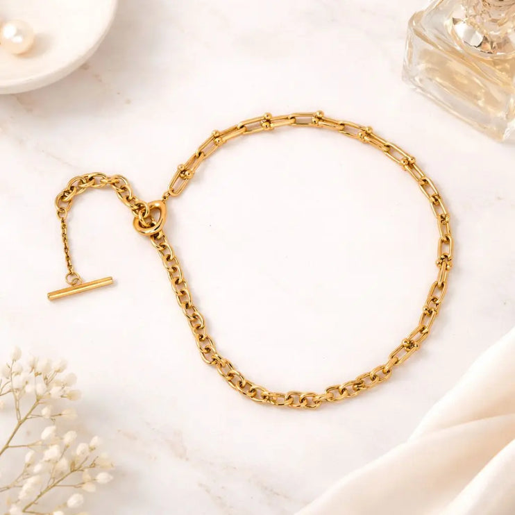 Gold chain bracelet on a light background with decorative elements