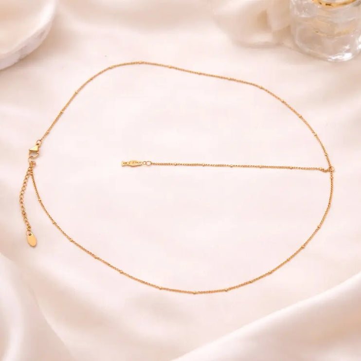 Gold necklace on a soft pink fabric background