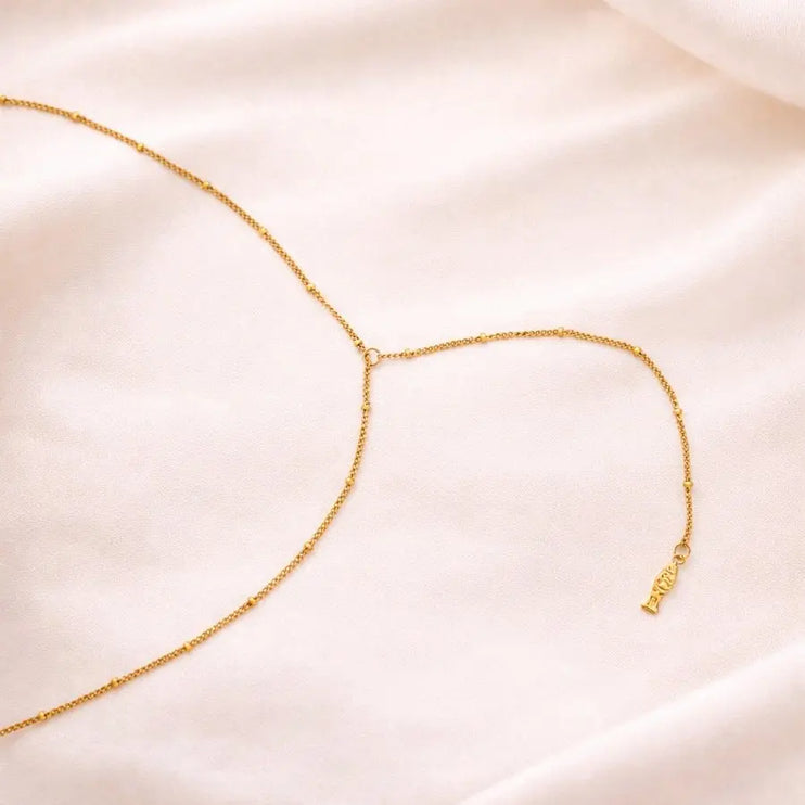 Gold necklace on a soft pink fabric background