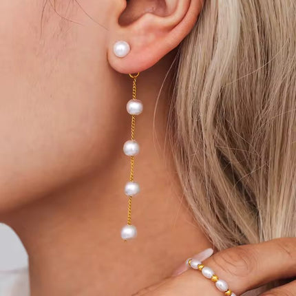 Pearl drop earrings being worn with a close-up of the ear and hair.