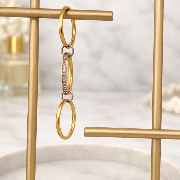 Gold hoop earrings hanging on a gold stand with a blurred background
