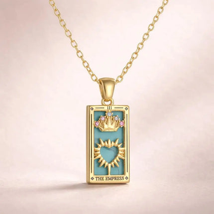 Gold pendant with 'The Empress' tarot card design on a beige background