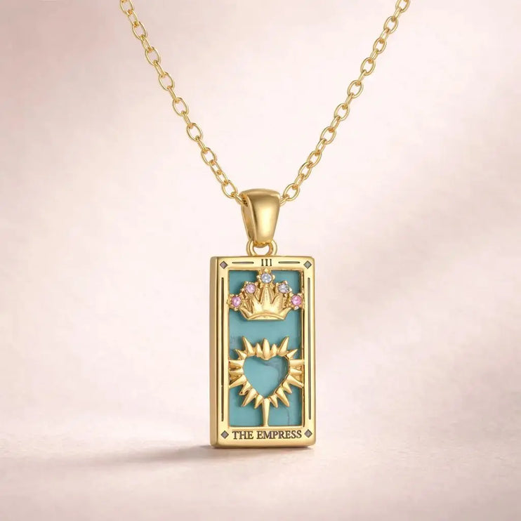 Gold pendant with 'The Empress' tarot card design on a beige background