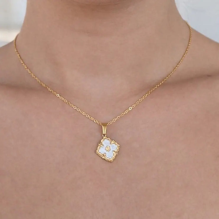 Gold necklace with a floral pendant on a person's neck