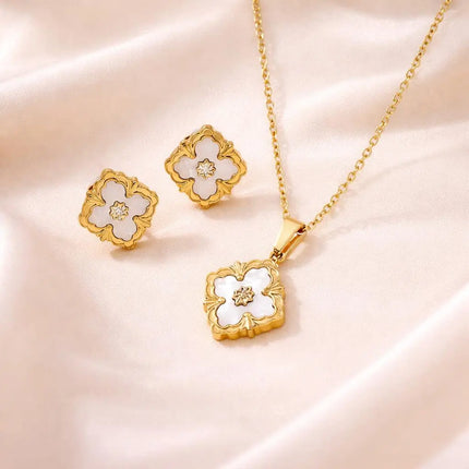 Gold jewelry set with floral designs on a soft pink background