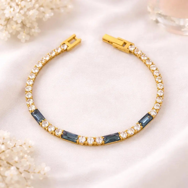 Gold bracelet with blue stones on a light background