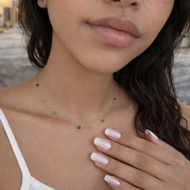 Close-up of a woman wearing a delicate necklace with a blurred background