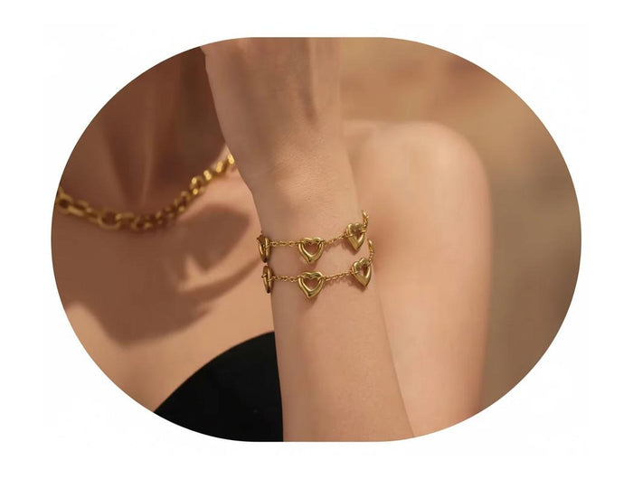 Gold anklet with heart-shaped links on a person's ankle against a neutral background