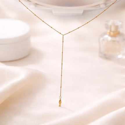 Gold necklace on a soft beige fabric background